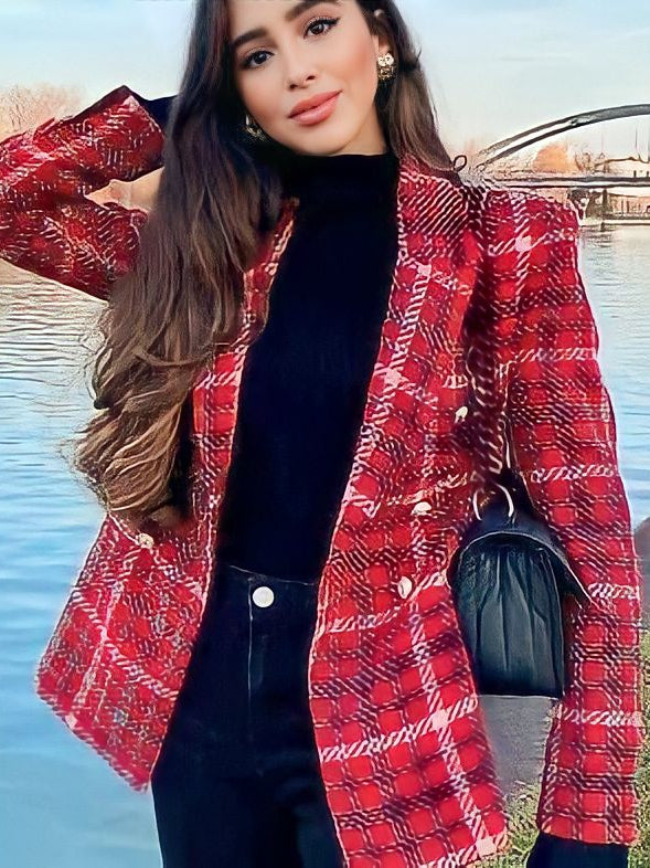 Woman in red plaid textured tweed blazer over black top and pants, holding a black quilted bag by a lakeside.