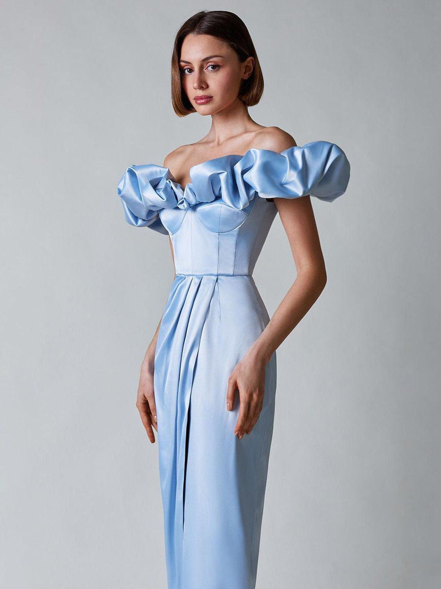 Slim model in pale blue satin off-shoulder tube dress with dramatic ruffled sleeves and a long pleated skirt.