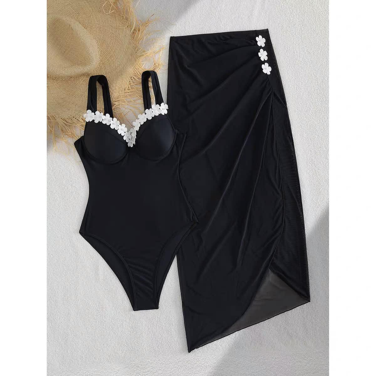Marbella Blossom Swimset: black one-piece swimsuit with white flower trim and matching black sarong wrap