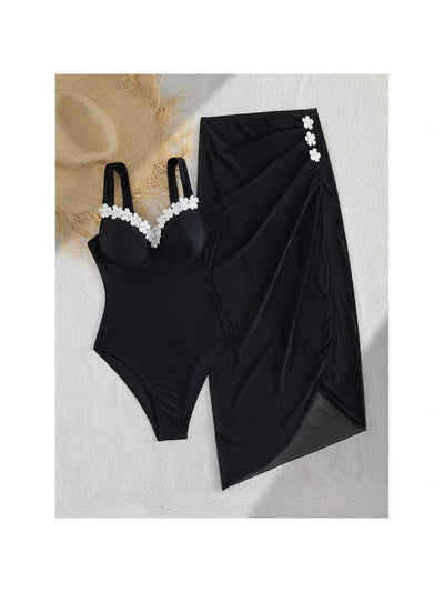 Marbella Blossom Swimset: black one-piece swimsuit with white flower trim and matching black sarong wrap