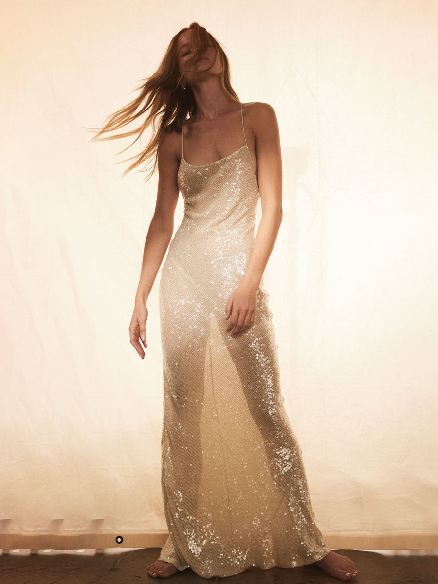 Champagne sequin spaghetti-strap backless slip maxi dress on a model, standing against a pale backdrop.