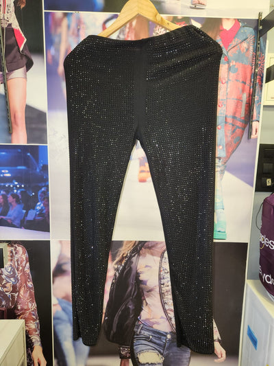 Black rhinestone pants on a wooden hanger, full-length with all-over sparkle, set against a fashion collage backdrop.