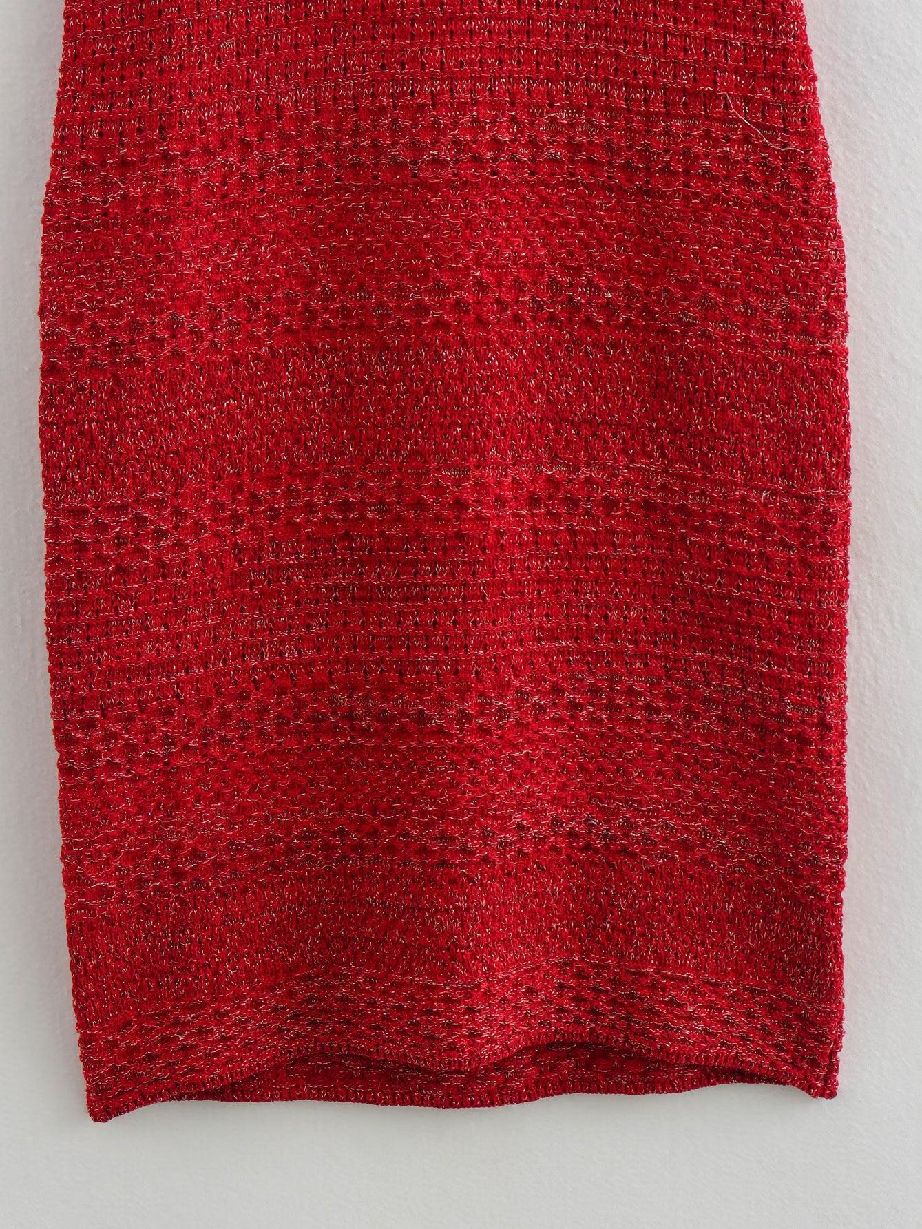 Close-up of red knitted dress fabric with horizontal striped bands, metallic thread shimmer, and a ribbed hem.