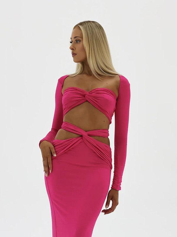 Model in hot-pink bandeau tube top with long sleeves and a matching high-waisted skirt with twisted midriff cutouts.