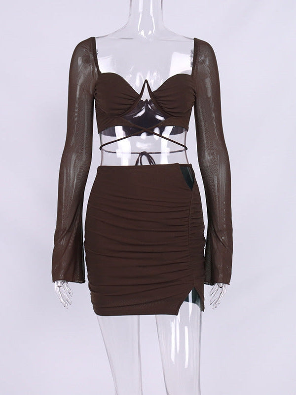 Brown cropped bustier top with sheer mesh sleeves and wrap ties, matched with a ruched high-waisted mini skirt with a left slit and dark panel.