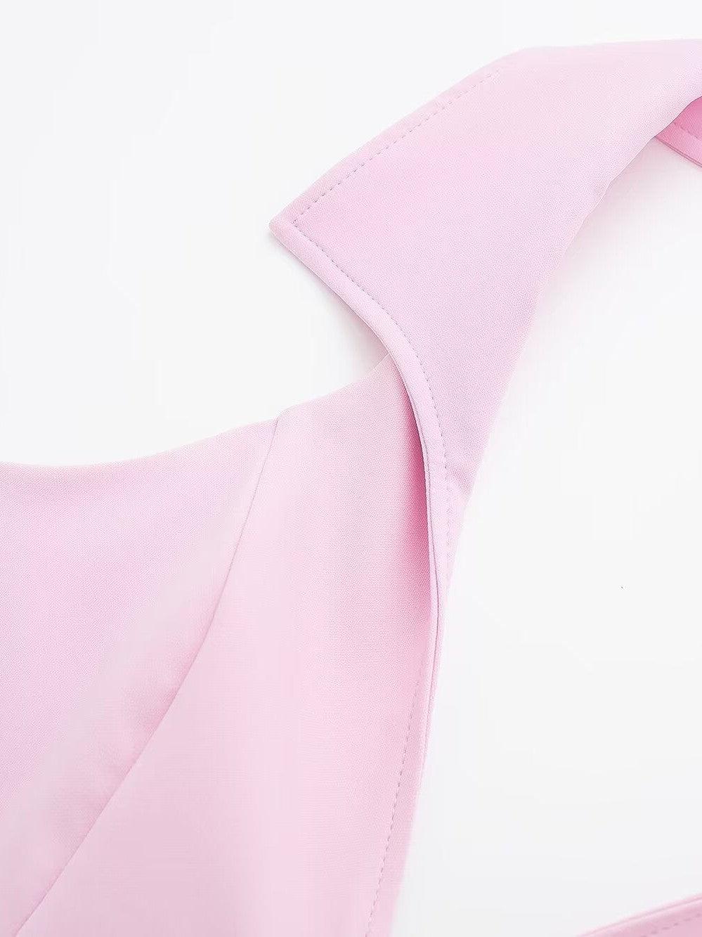 Close-up of pale pink fabric showing a halterneck strap and curved shoulder panel with neat topstitching.