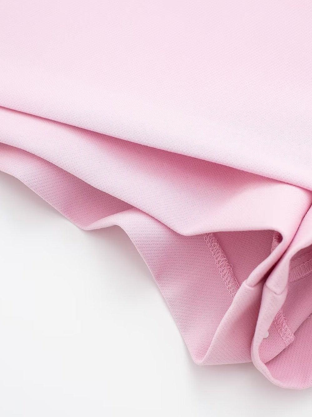 Close-up of soft pink fabric with layered folds and visible edge stitching.