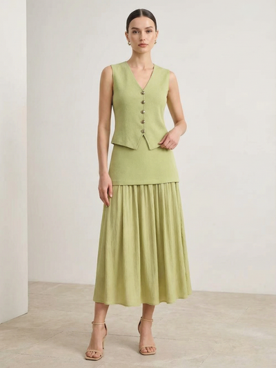 Light green knitted vest with V-neck and button-front, paired with a matching high-waist pleated midi skirt; nude heels.