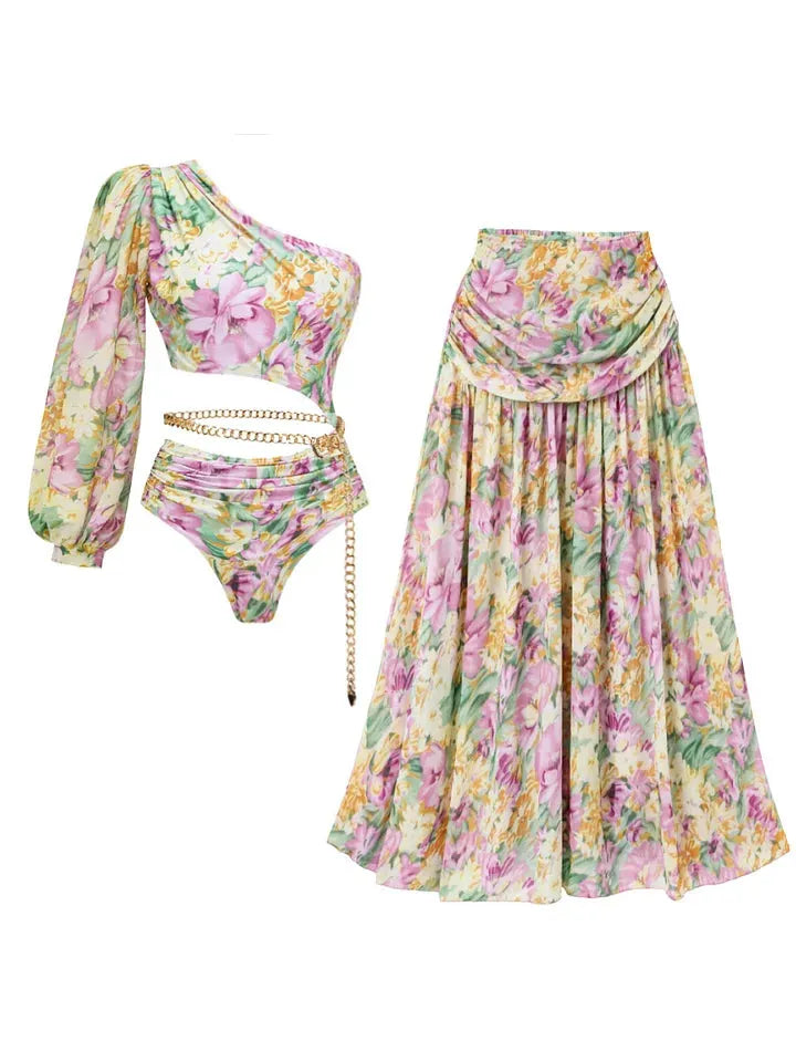 Pastel blossom print one-shoulder top with long sleeve and cutout; high-waist bottom with chain belt and draped skirt
