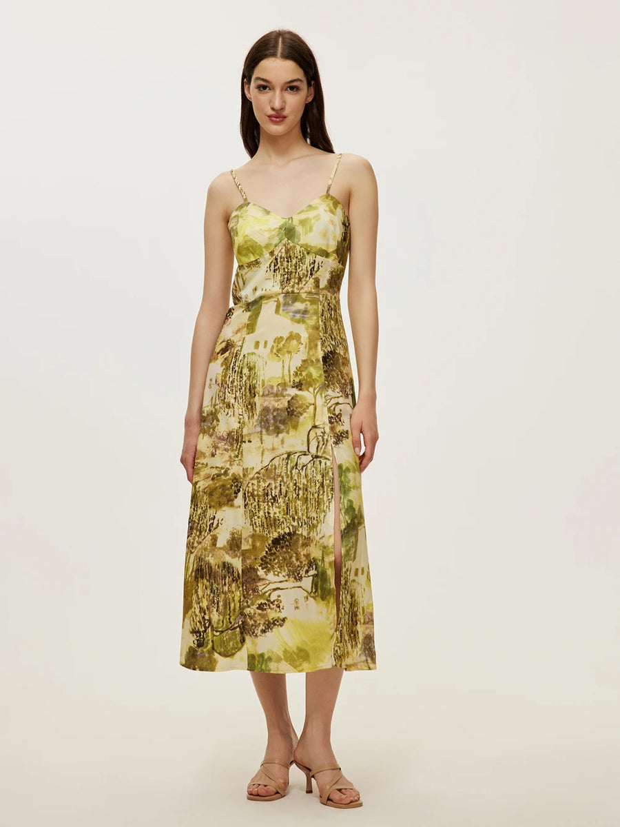 Model wearing a yellow-green floral print spaghetti-strap bustier midi dress with a side slit and nude sandals.