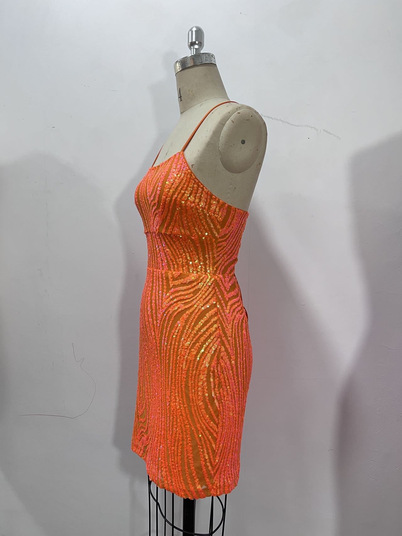 Orange sequined mini dress with a corset-inspired bodice, pink zebra-like pattern, and thin spaghetti straps.