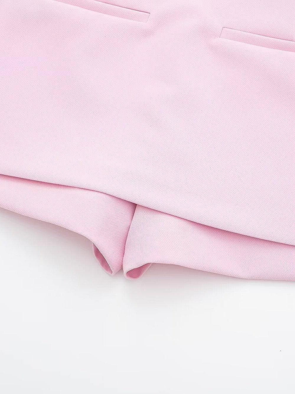 Pastel pink textured fabric close-up with two slim pocket slits and a curved folded hem.