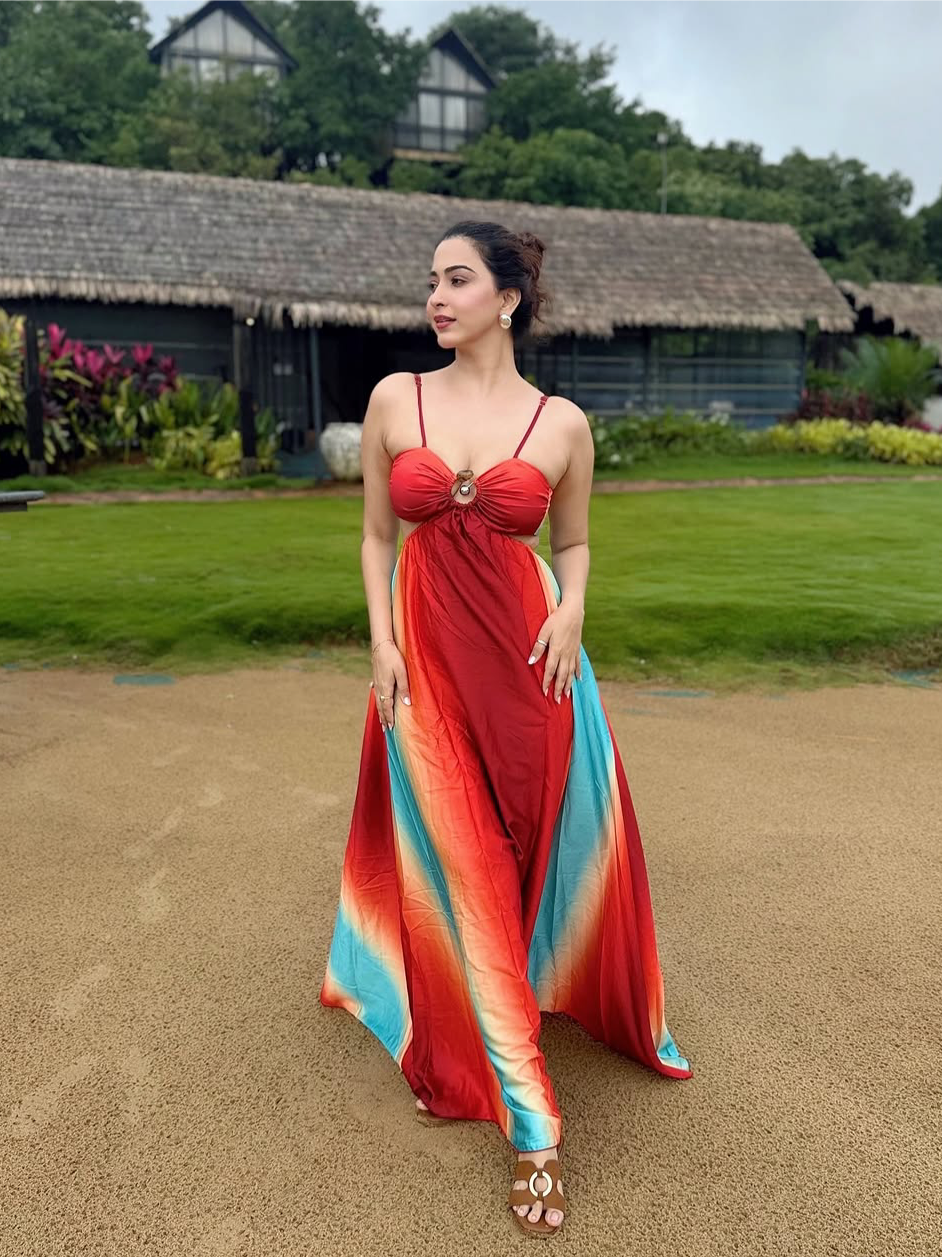 Model in gradient red-to-teal tie-dye cutout maxi dress with ring detail and thin straps, outdoors.