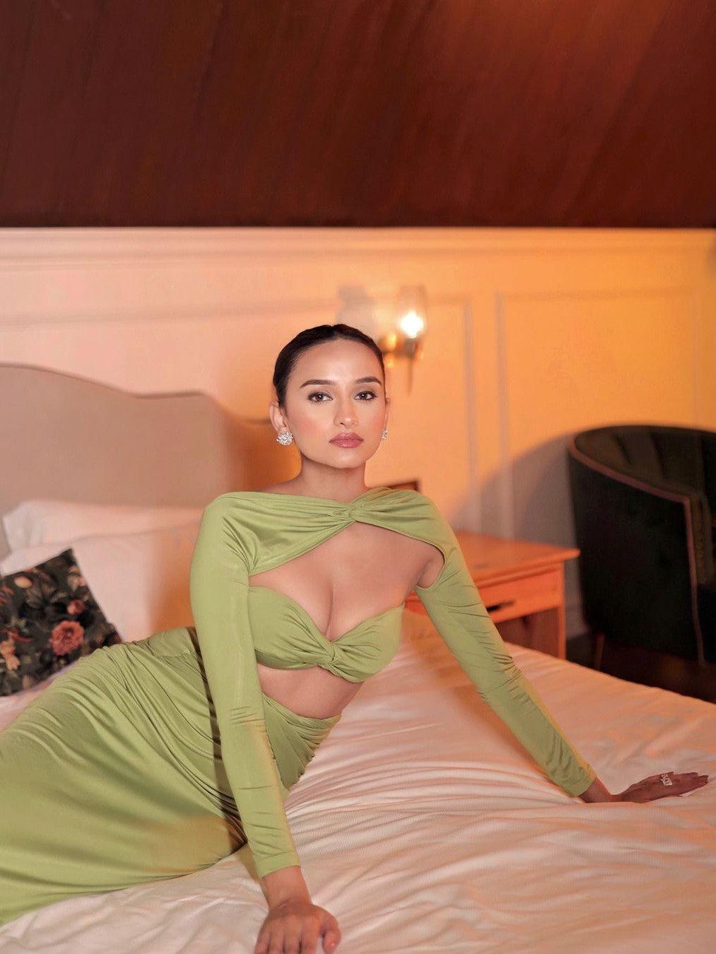 Model in lime green bandeau tube top with twist-front cutout and matching high-waisted skirt, posed on a bed.