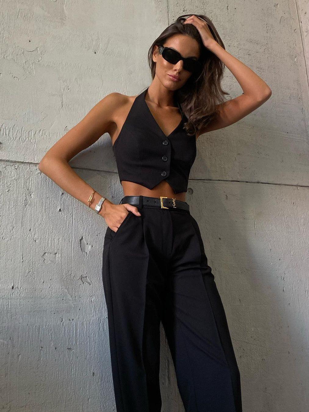 Black cropped waistcoat with button front and high-waisted wide-leg pants; belt and sunglasses.