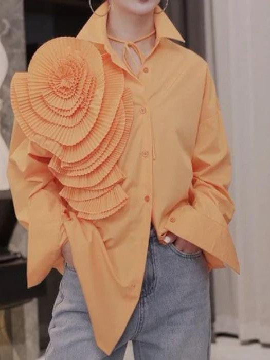 Peach oversized button-down shirt with a large pleated rosette on the left shoulder; model wearing jeans.