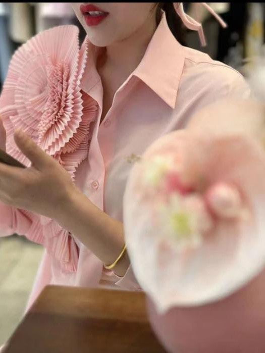 Light pink long-sleeve button-down shirt with a large pleated pink flower patch on the chest.