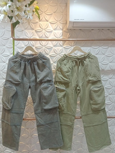 Gray-blue and olive cargo wide-leg pants with oversized patch pockets and zippered side pockets, on wooden hangers.