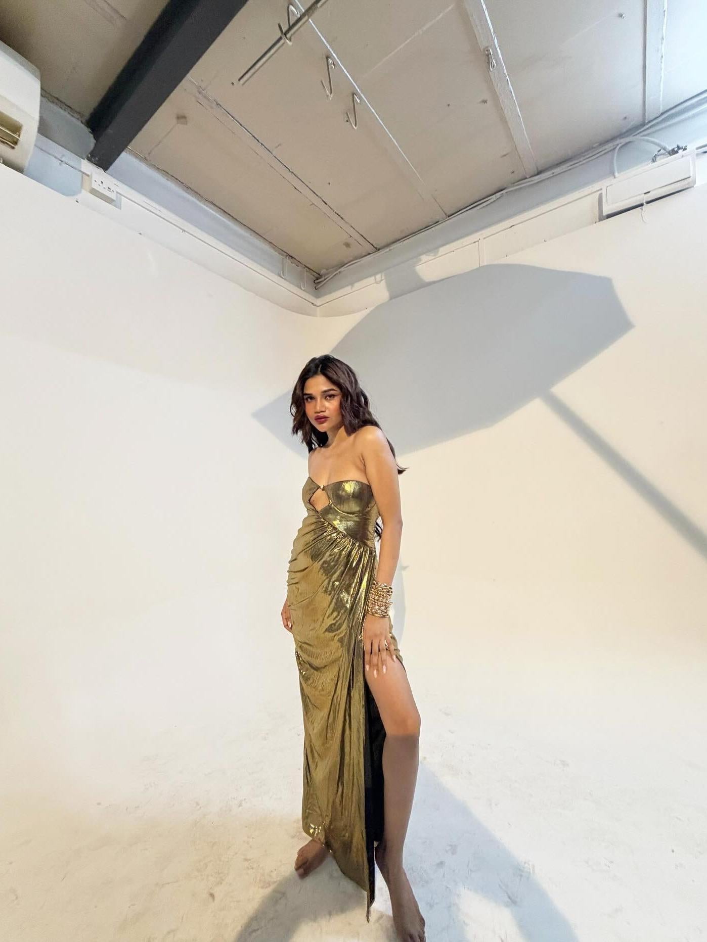 Gold metallic pleated strapless cut-out maxi dress worn by a model in a studio setting