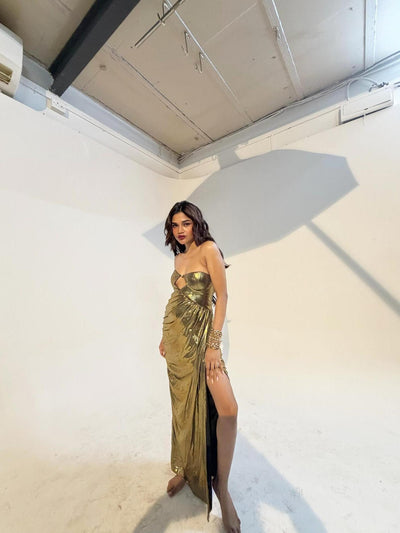 Gold metallic pleated strapless cut-out maxi dress worn by a model in a studio setting