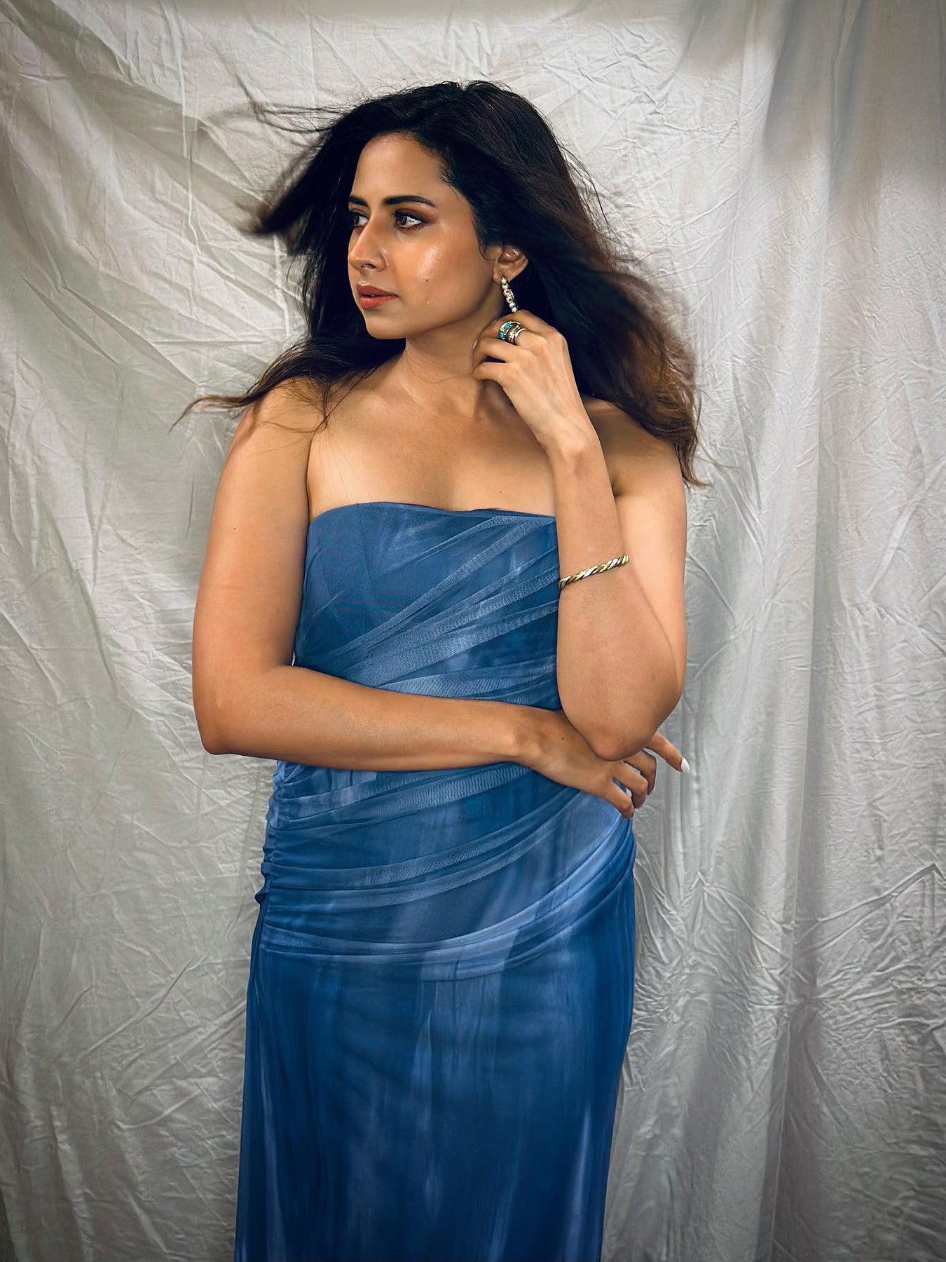 Blue tie-dye mesh strapless tube dress with ruched draped panels, model posing with hand near face and wearing earrings.
