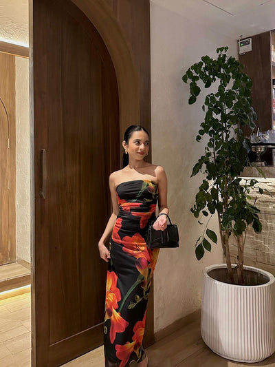 Strapless black tube dress with bold red-orange floral print, form-fitting maxi length.