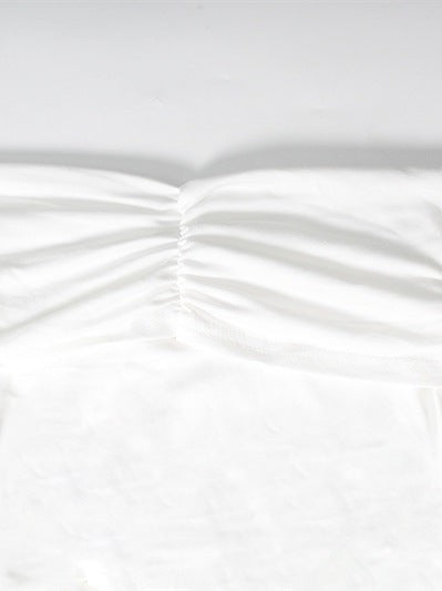 Close-up of white fabric with a central ruched seam and soft, gathered folds.