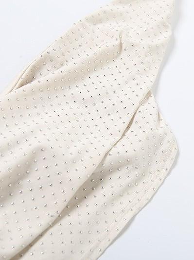 Cream fabric close-up with evenly spaced tiny rhinestones creating a dotted texture.