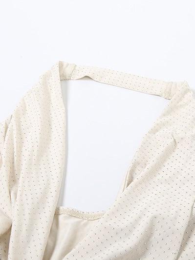 Cream halter-neck backless dress with tiny polka dots and a slim fitted sheath silhouette.