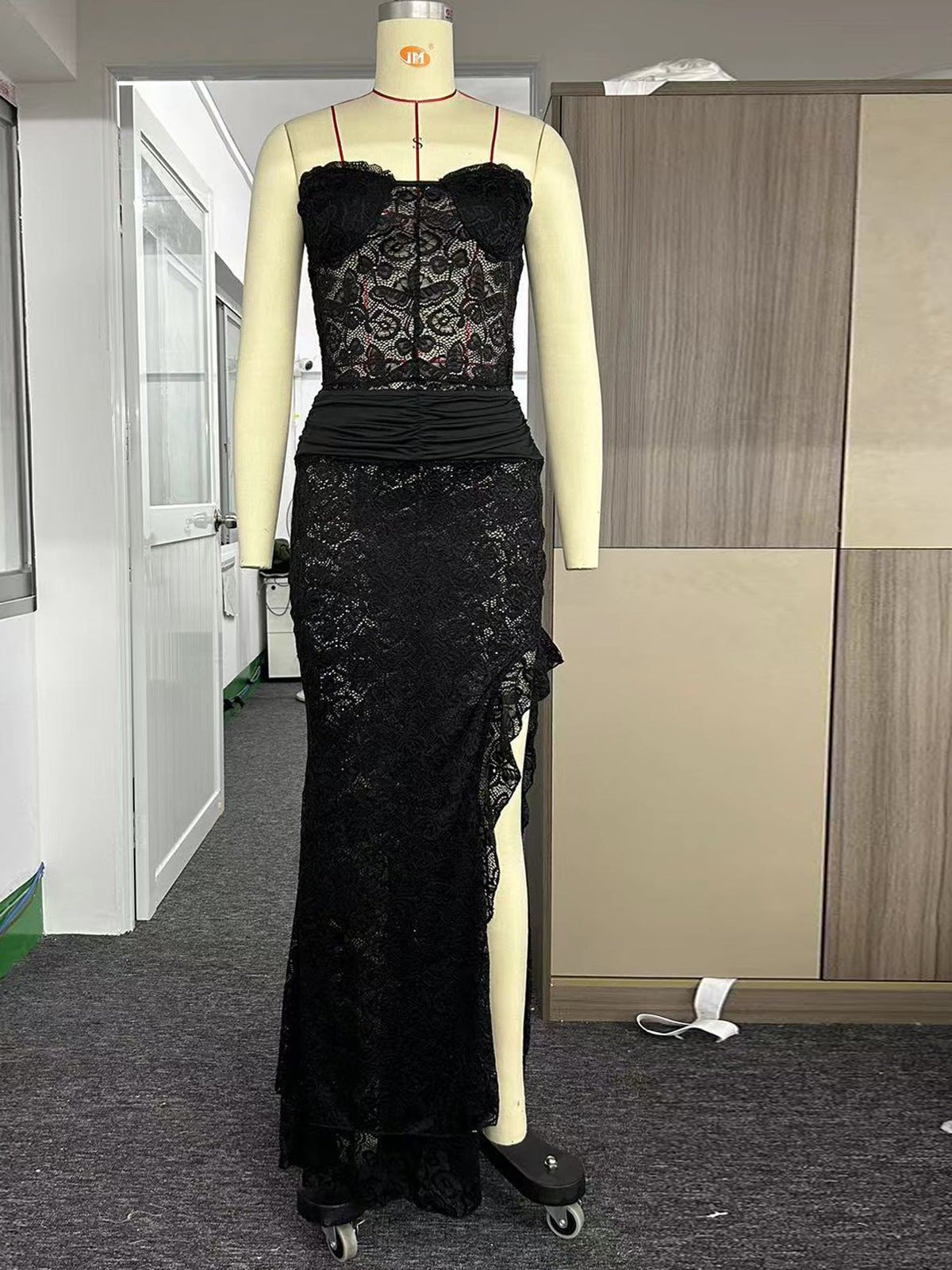 Black lace strapless sheath dress with sheer floral overlay, ruched waist, and irregular asymmetric side slit.