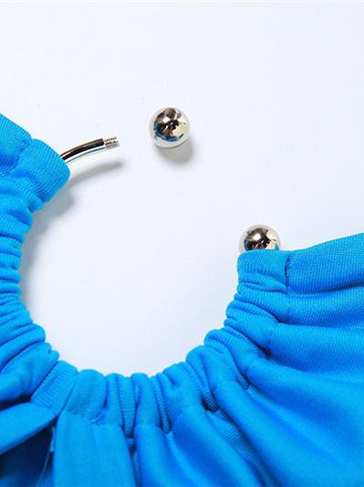Electric blue ruched fabric close-up with two silver ball stud earrings on white background