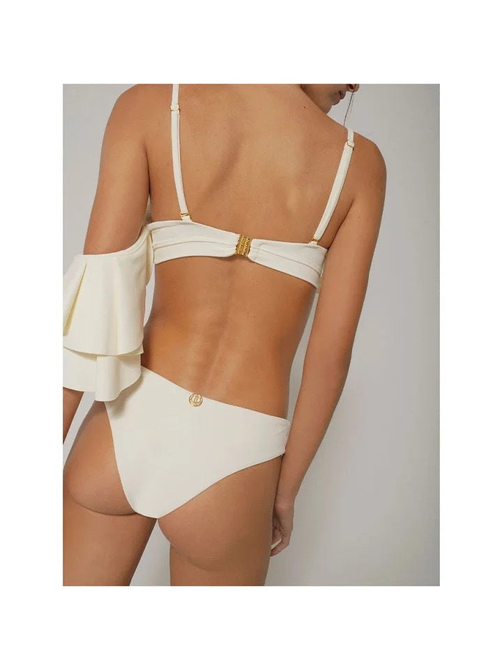 Back view of cream bikini with slim straps, center gold clasp, high-cut bottom, and large white ruffle on left.