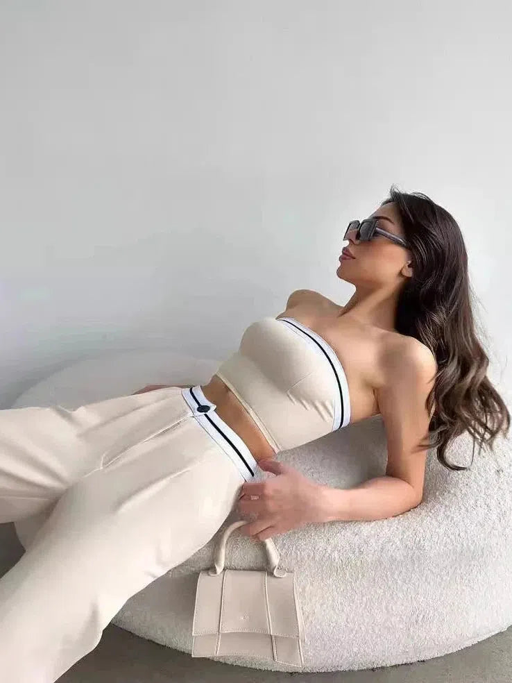 Cream striped tube top with navy edges and matching wide-leg pants; model lounging on a white textured sofa with a beige handbag.