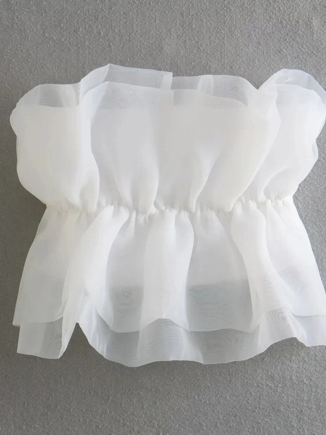White organza bandeau top with stacked sheer ruffles and elastic waist, creating a voluminous peplum.