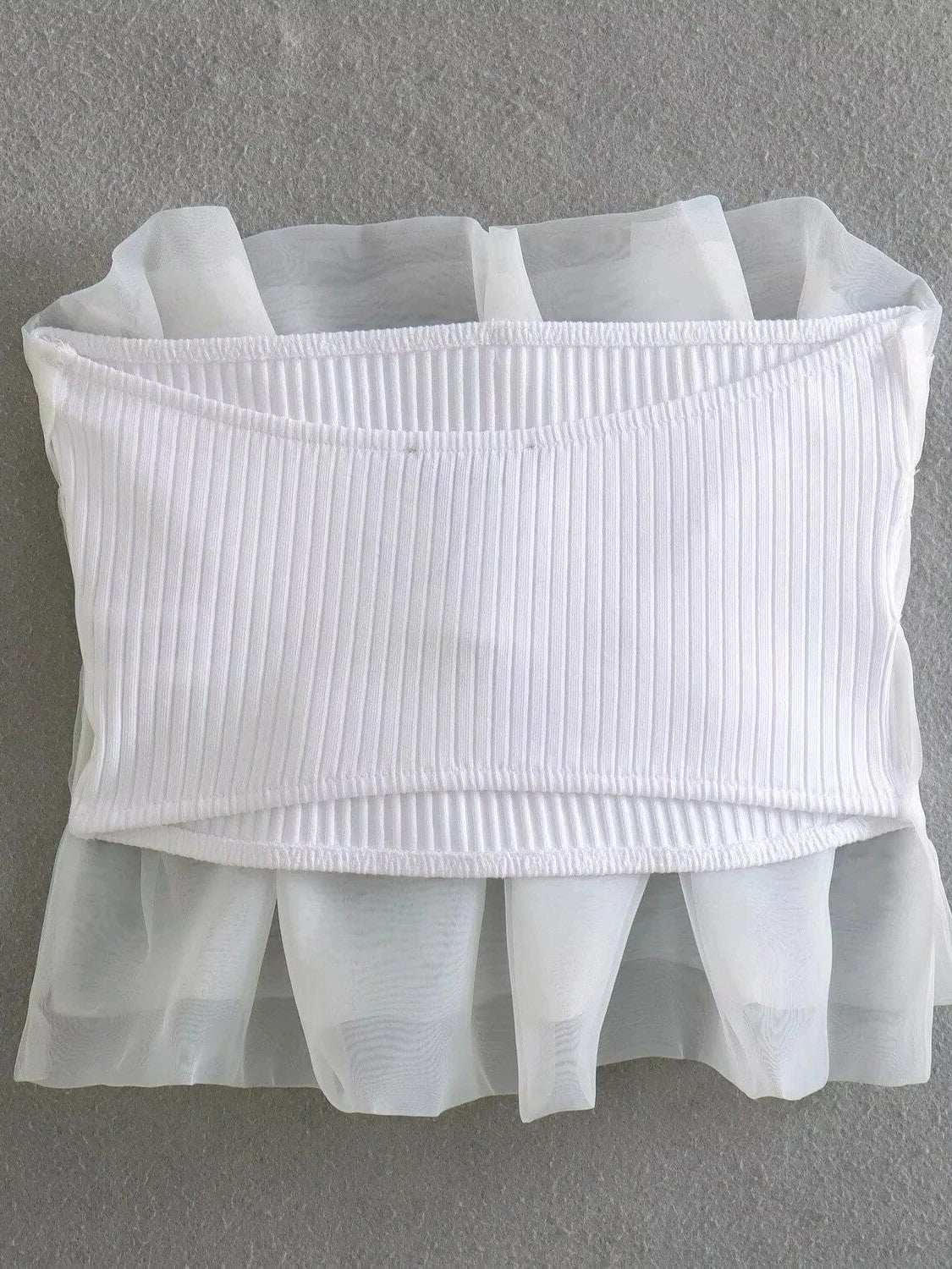 White bandeau top with vertical ribbing and sheer organza overlay forming a fluttery hem.