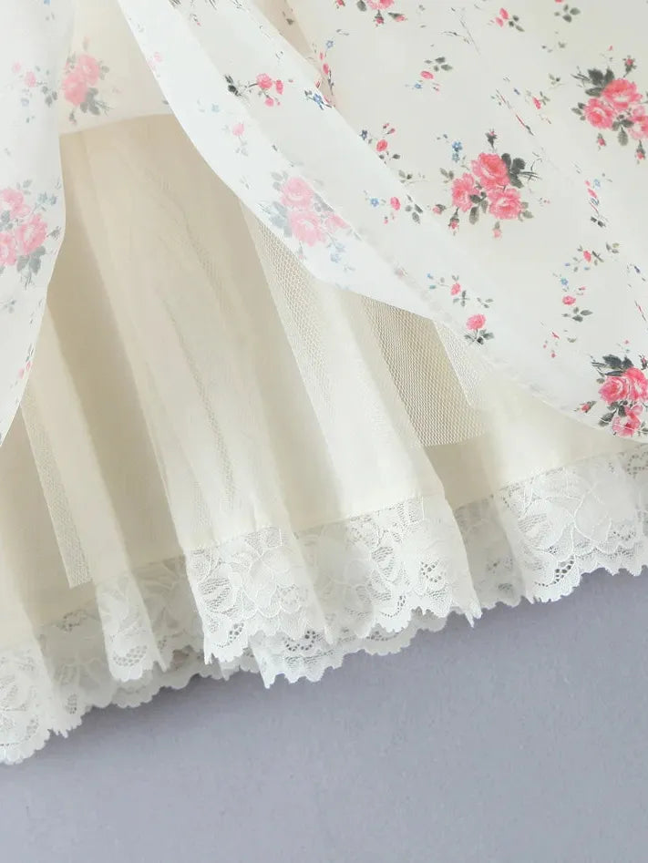Cream mini dress with sheer floral overlay featuring pink roses, layered cream lining, and scalloped lace hem.