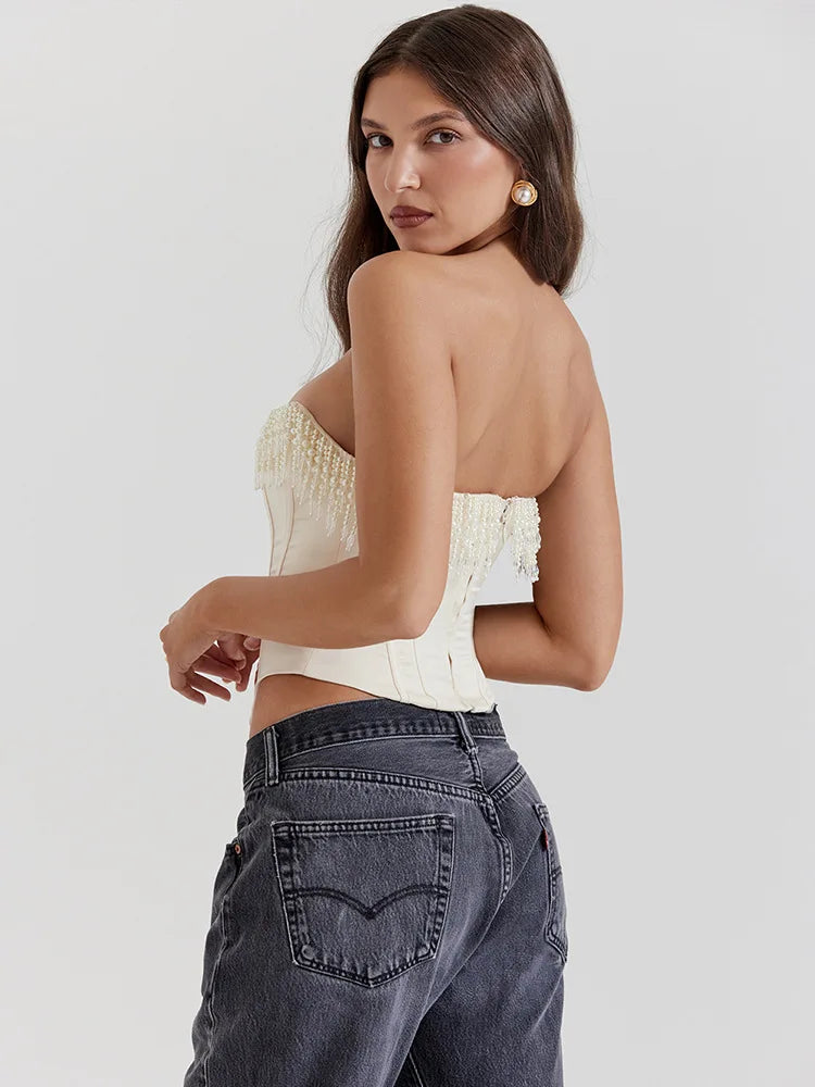 Cream beaded fringe strapless corset top with fringe along the upper edge, shown from the back on a model in dark jeans.