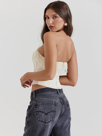 Cream beaded fringe strapless corset top with fringe along the upper edge, shown from the back on a model in dark jeans.