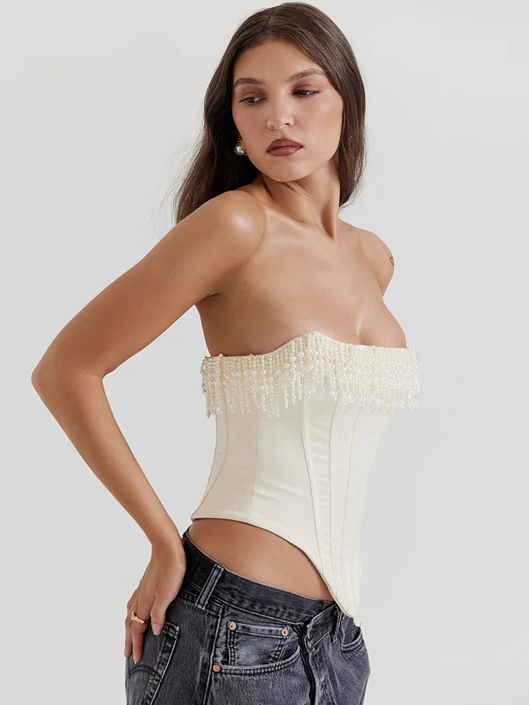 Ivory strapless corset top with beaded fringe along the neckline and vertical seam panels, worn with dark jeans.