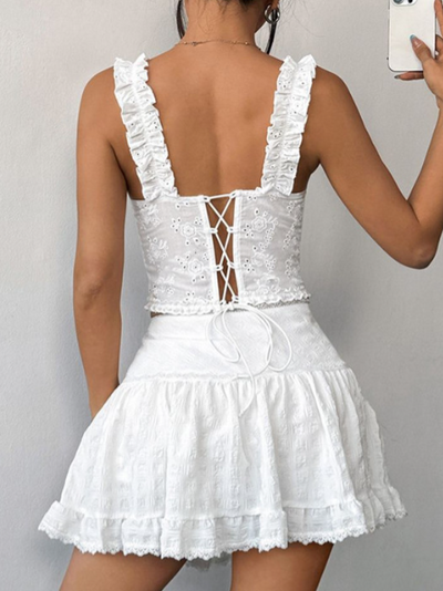 Back view of white eyelet lace-up corset top with ruffled straps and crisscross lacing, tied at the waist.