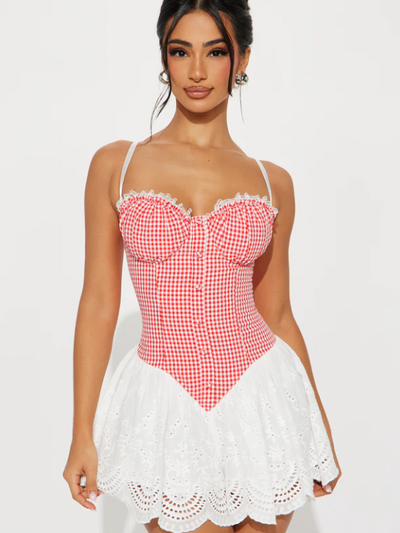 Model wearing red gingham bustier mini dress with white lace trim and eyelet skirt with scalloped hem.