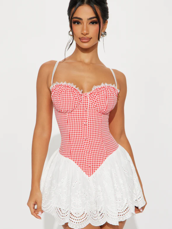 Model wearing red gingham bustier mini dress with white lace trim and eyelet skirt with scalloped hem.