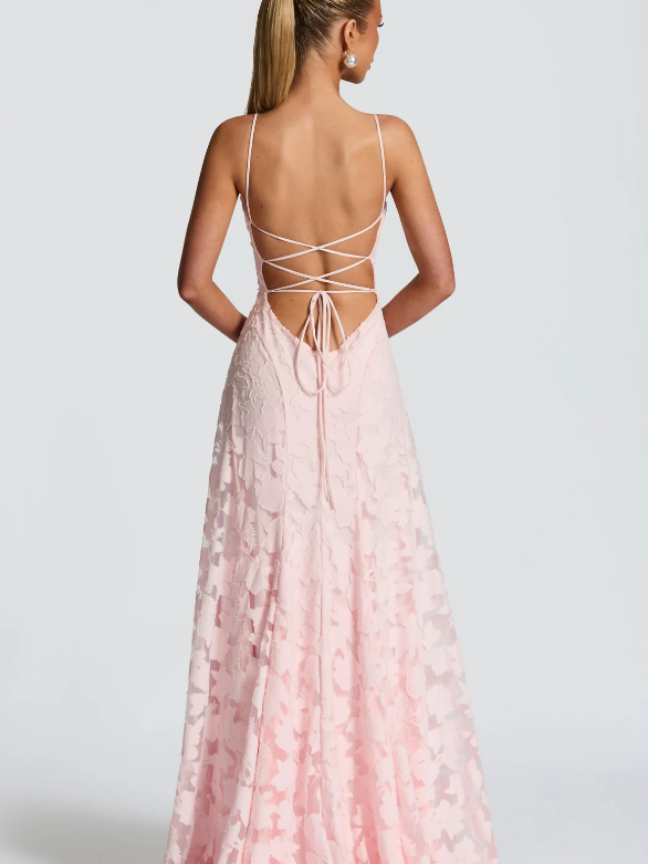 Back view of a pale pink floral-appliqué maxi dress with spaghetti straps and a crisscross lace-up back.