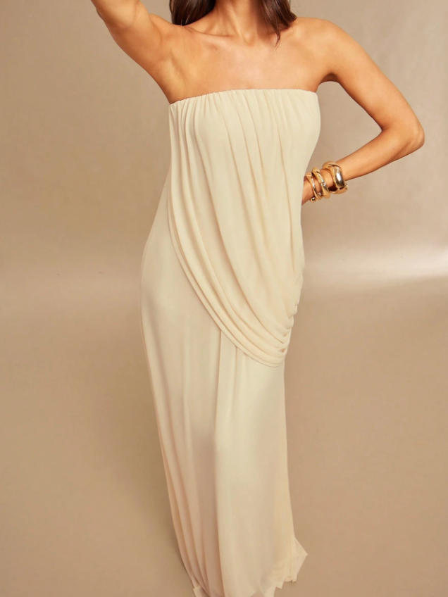 Ivory strapless draped maxi dress on a model with a side-hip gathered drape and flowing skirt, wearing gold bracelets.