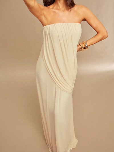 Ivory strapless draped maxi dress on a model with a side-hip gathered drape and flowing skirt, wearing gold bracelets.