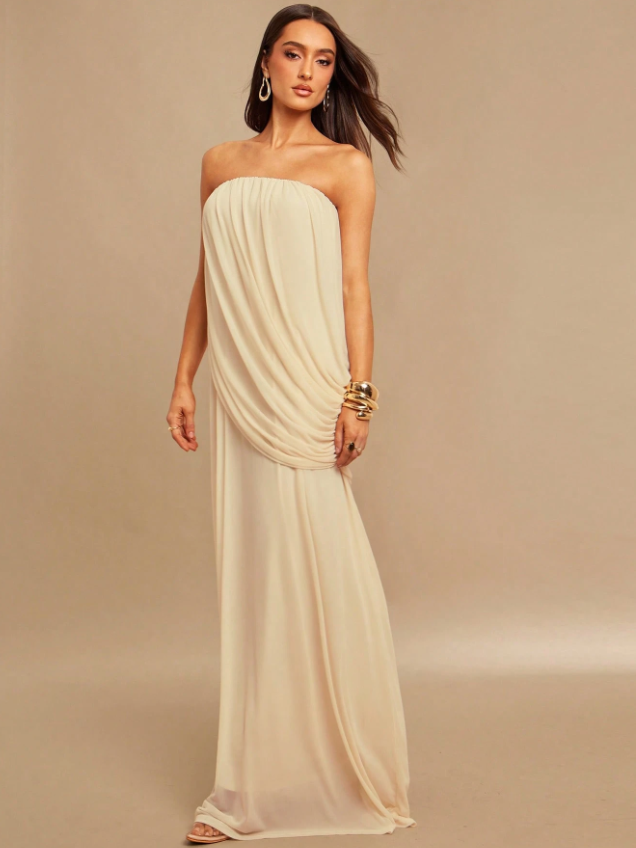 Ivory strapless draped maxi dress on a model, floor-length with sweeping drape at the hip, wearing gold bangles.