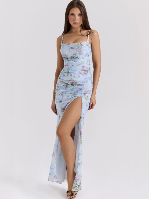 Sky blue floral ruched maxi dress with thin straps and a high front slit, worn by a model.