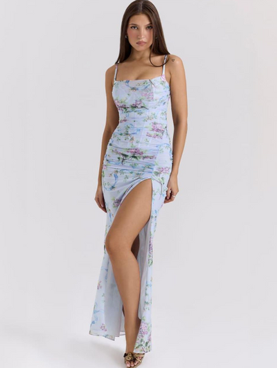 Sky blue floral ruched maxi dress with thin straps and a high front slit, worn by a model.