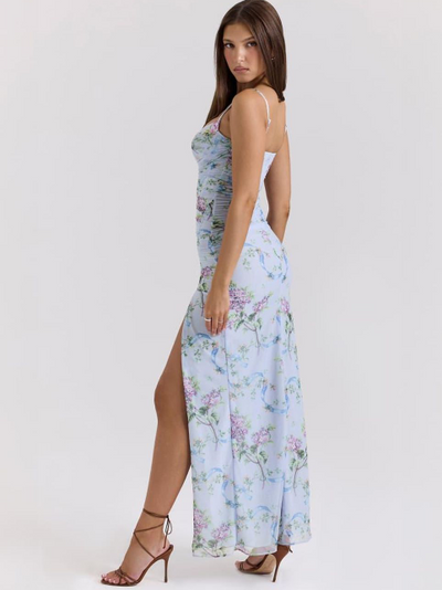 Model in sky blue floral ruched maxi dress with spaghetti straps, side slit, paired with brown strappy heels.