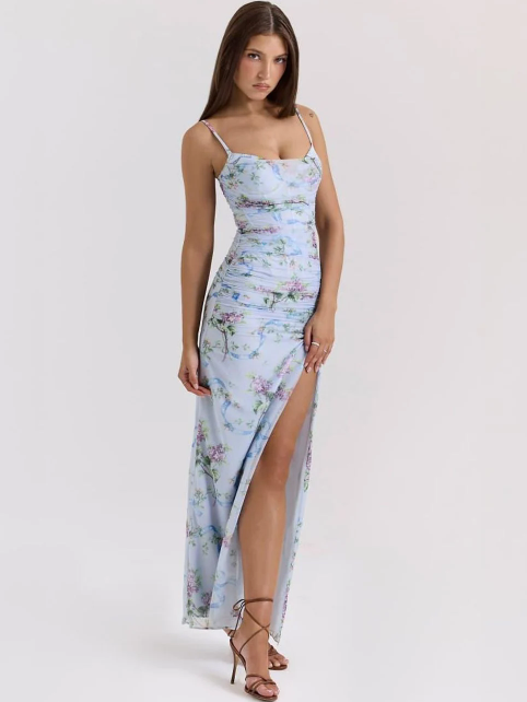 Model wearing sky-blue floral ruched maxi dress with spaghetti straps and high thigh slit, white studio backdrop.